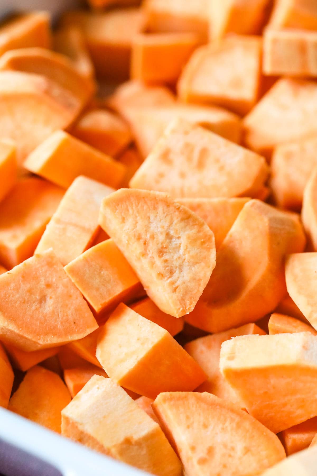Close-up view of chopped sweet potatoes in a baking dish.