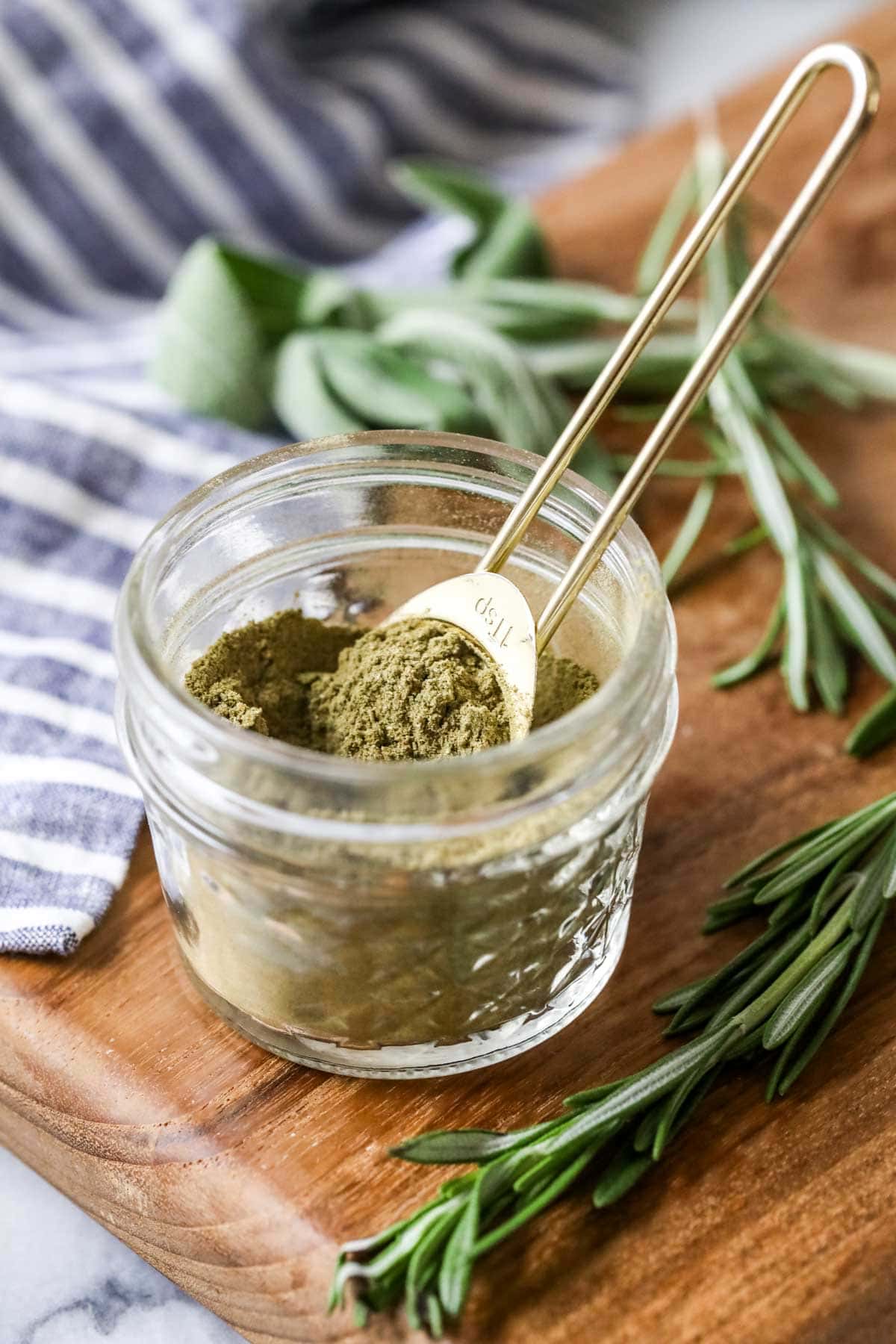 Small jar of homemade seasoning with a gold measuring spoon inside.