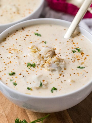 Bowl of cream of crab soup topped with old bay, parsley, and crab meat.