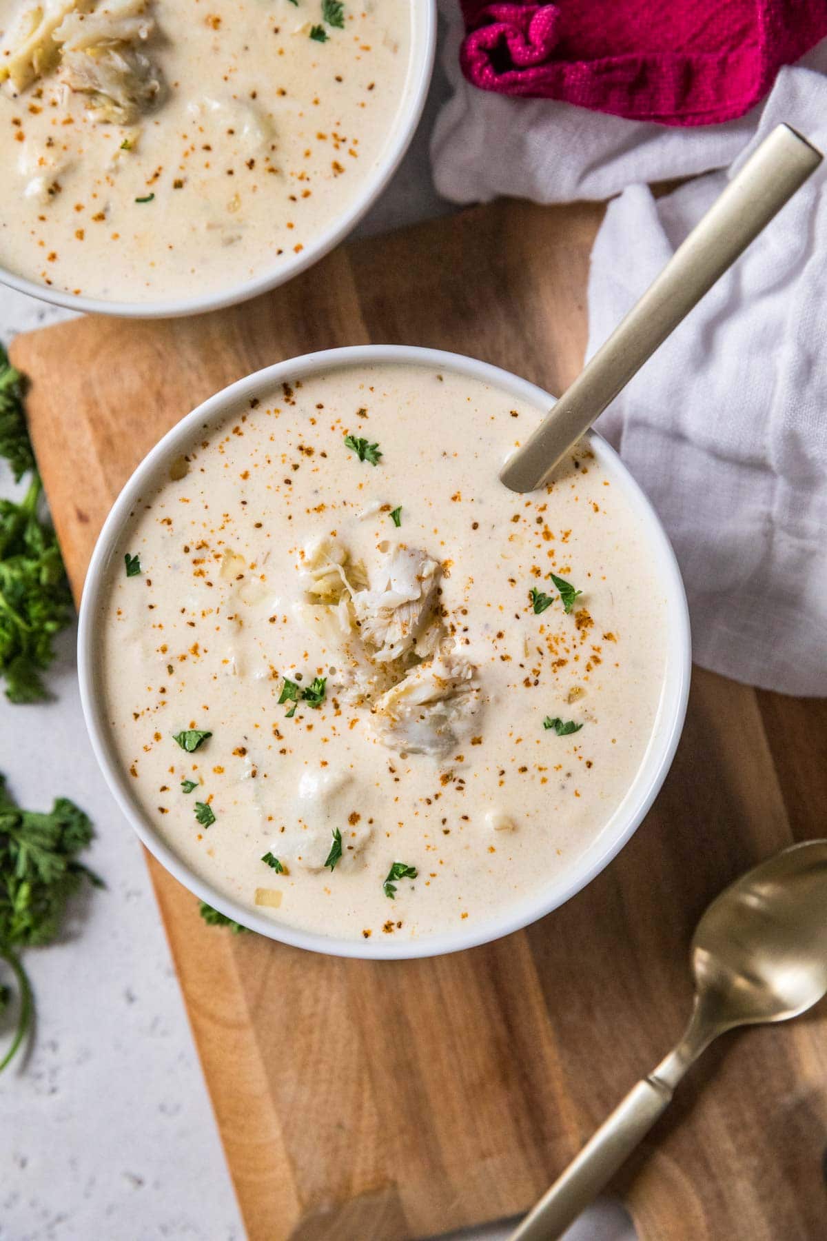 Overhead view of a bowl of cream of crab soup topped with old bay, parsley, and crab meat.