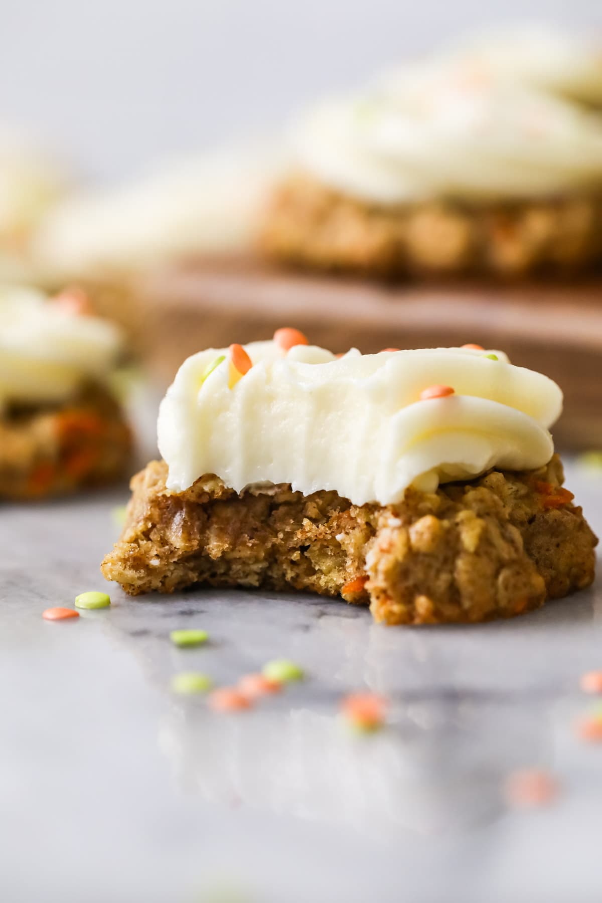 Bite missing from a cookie made with carrots, oats, and walnuts.