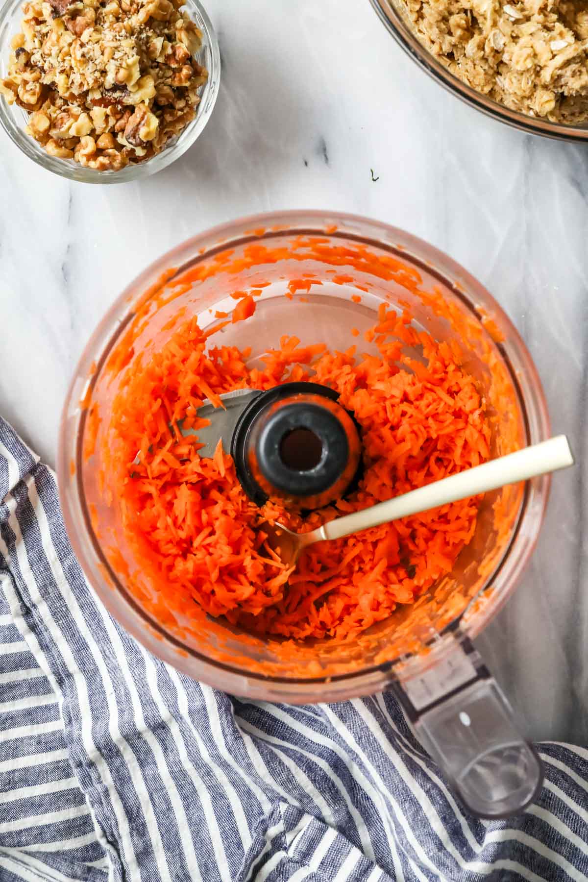 Overhead view of shredded carrots in a food processor bowl.