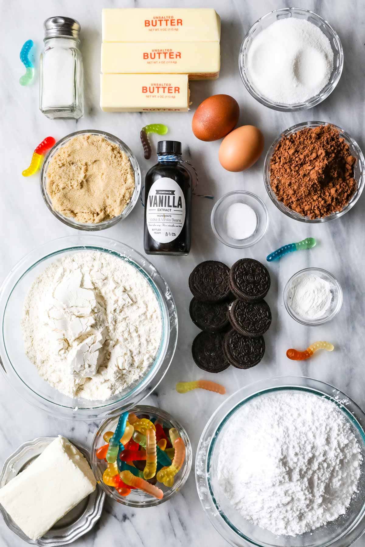 Overhead view of ingredients including cocoa powder, gummy worms, Oreos, and more.