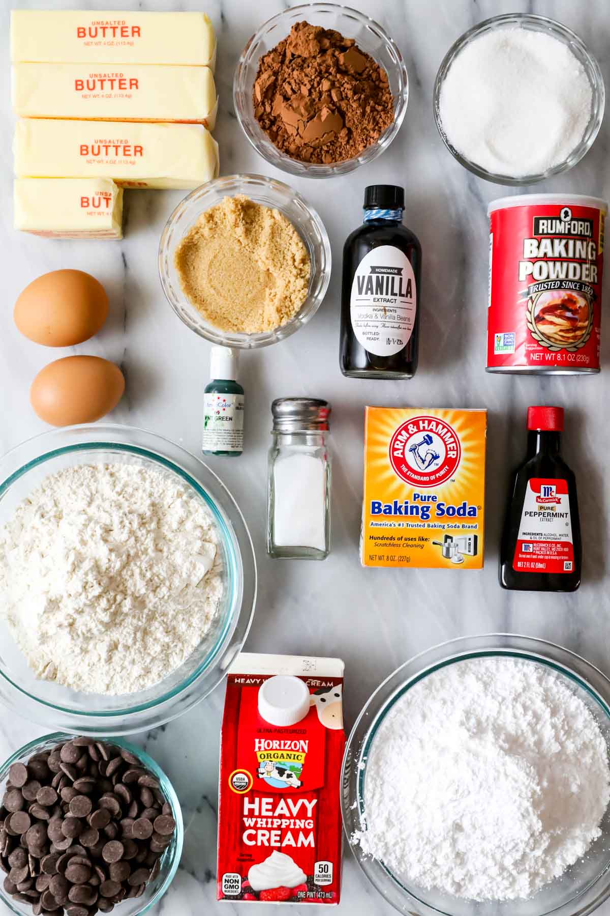 Overhead view of ingredients including cocoa powder, peppermint extract, green food coloring, and more.