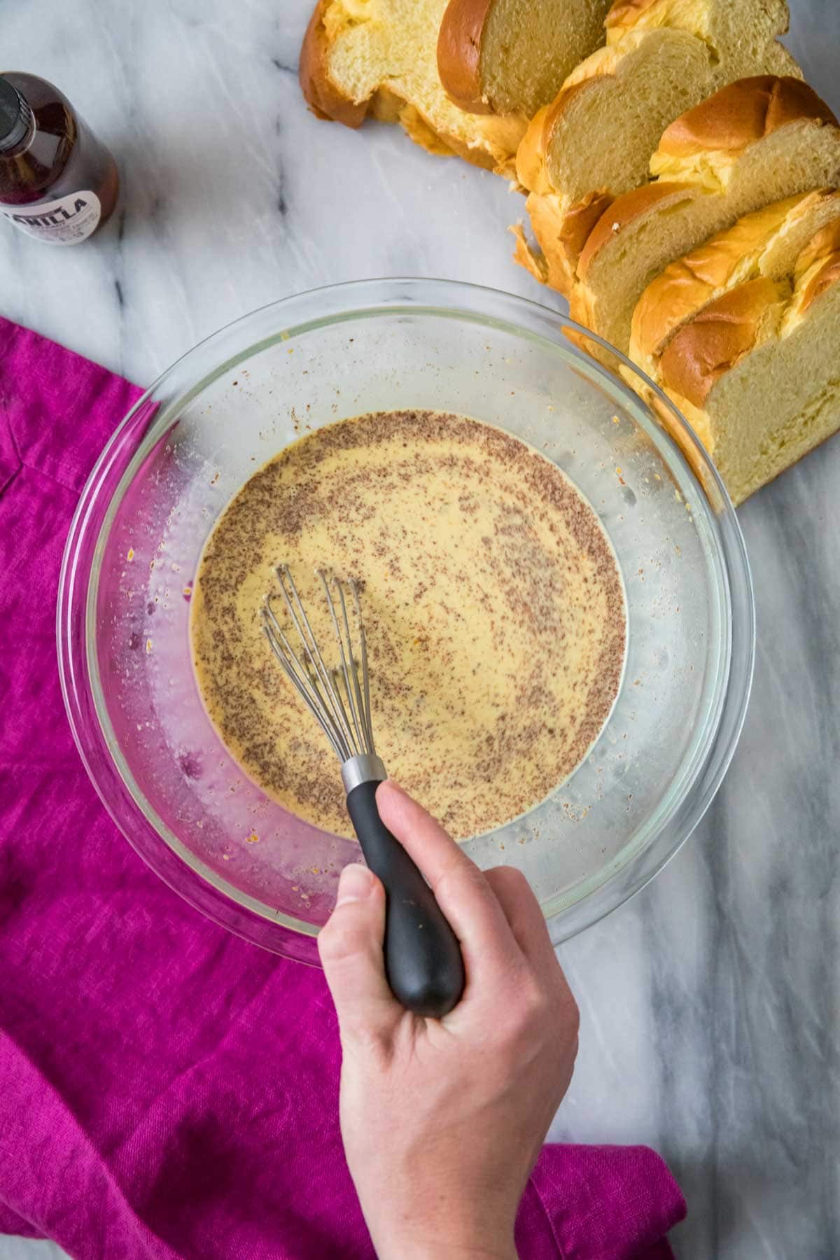 Overhead view of a custard mixture being combined with cinnamon and orange zest.