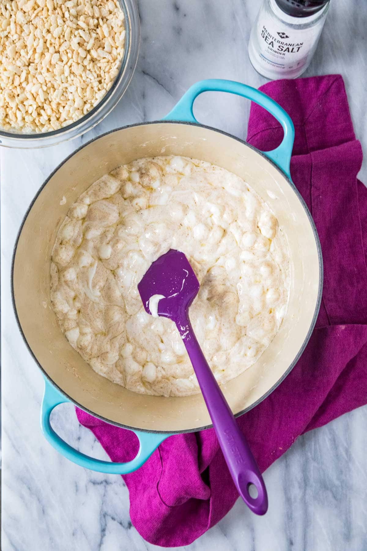 Overhead view of mini marshmallows melting into brown butter in a saucepan.