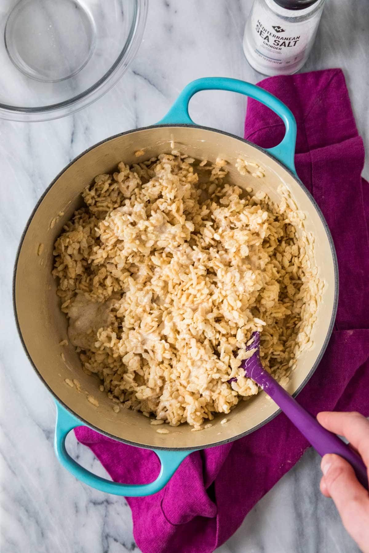 Overhead view of rice krispies cereal being combined with melted marshmallow and brown butter.