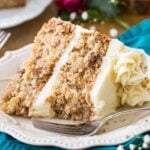 Slice of cream cheese frosted hummingbird cake on a white plate