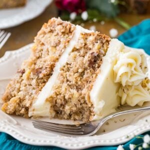 Slice of cream cheese frosted hummingbird cake on a white plate