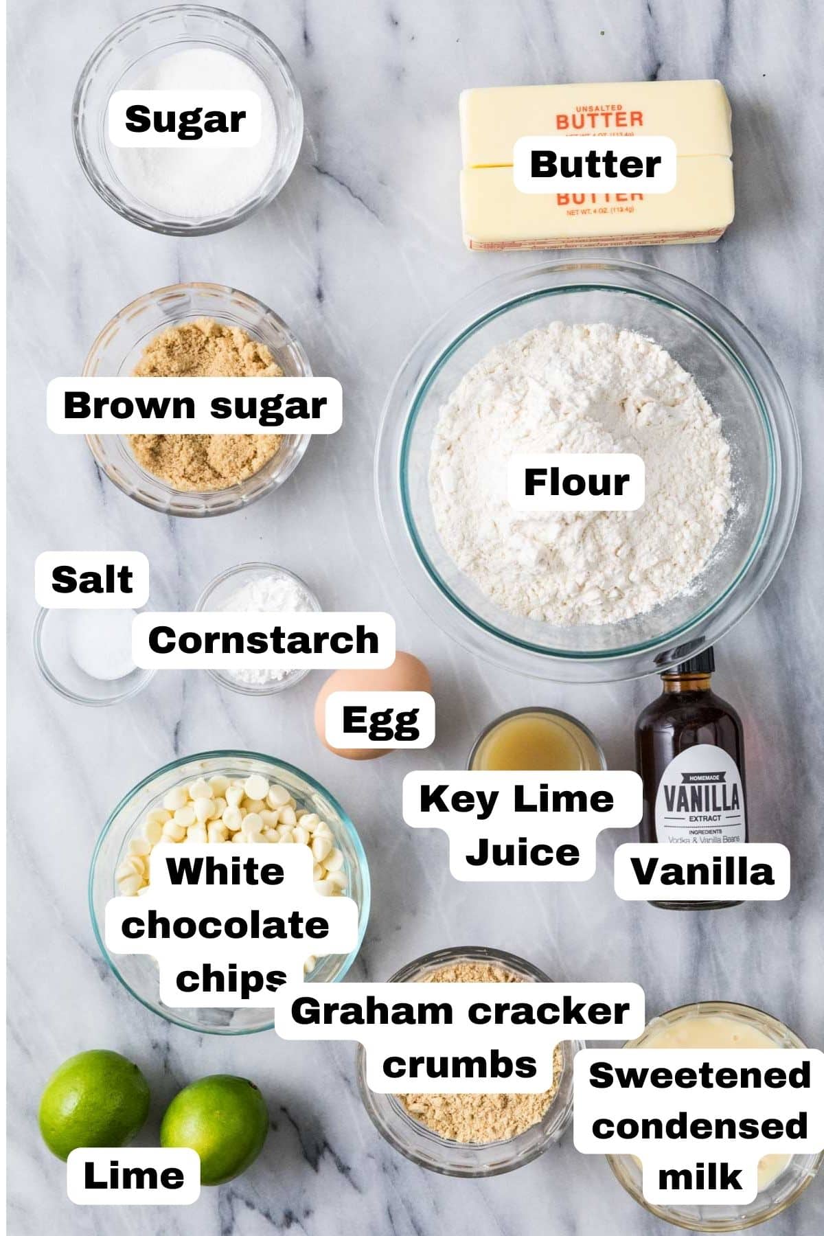 Overhead view of labelled ingredients including limes, key lime juice, graham cracker crumbs, and more.