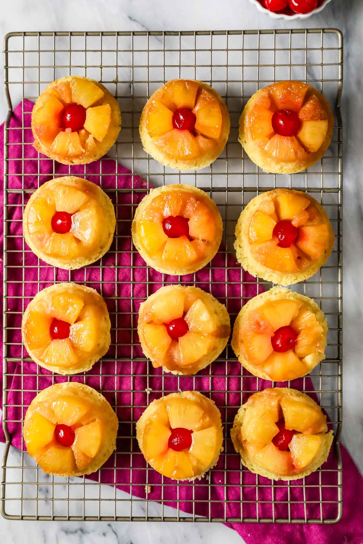 Overhead view of pineapple upside down cupcakes on a cooling rack.
