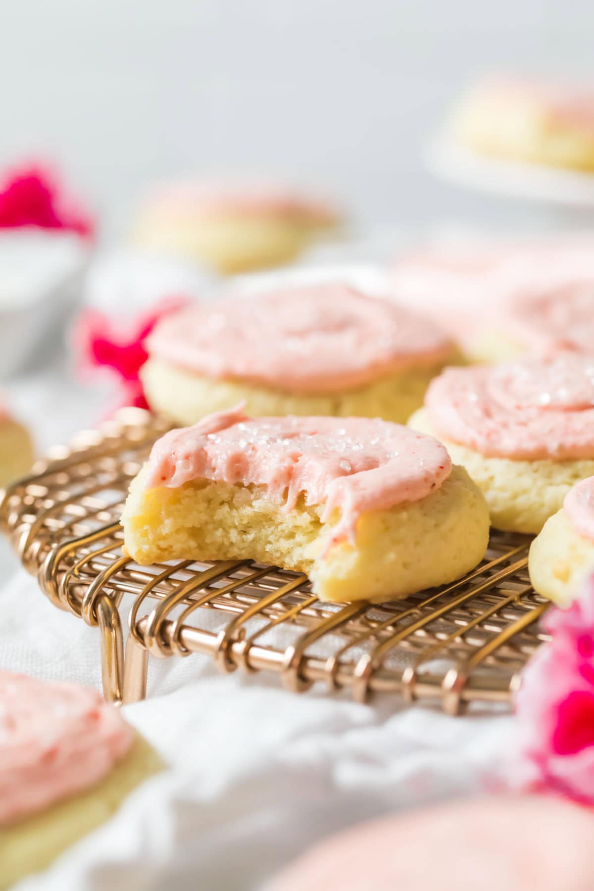 Bite missing from a thick, cakey cookie topped with pink frosting.