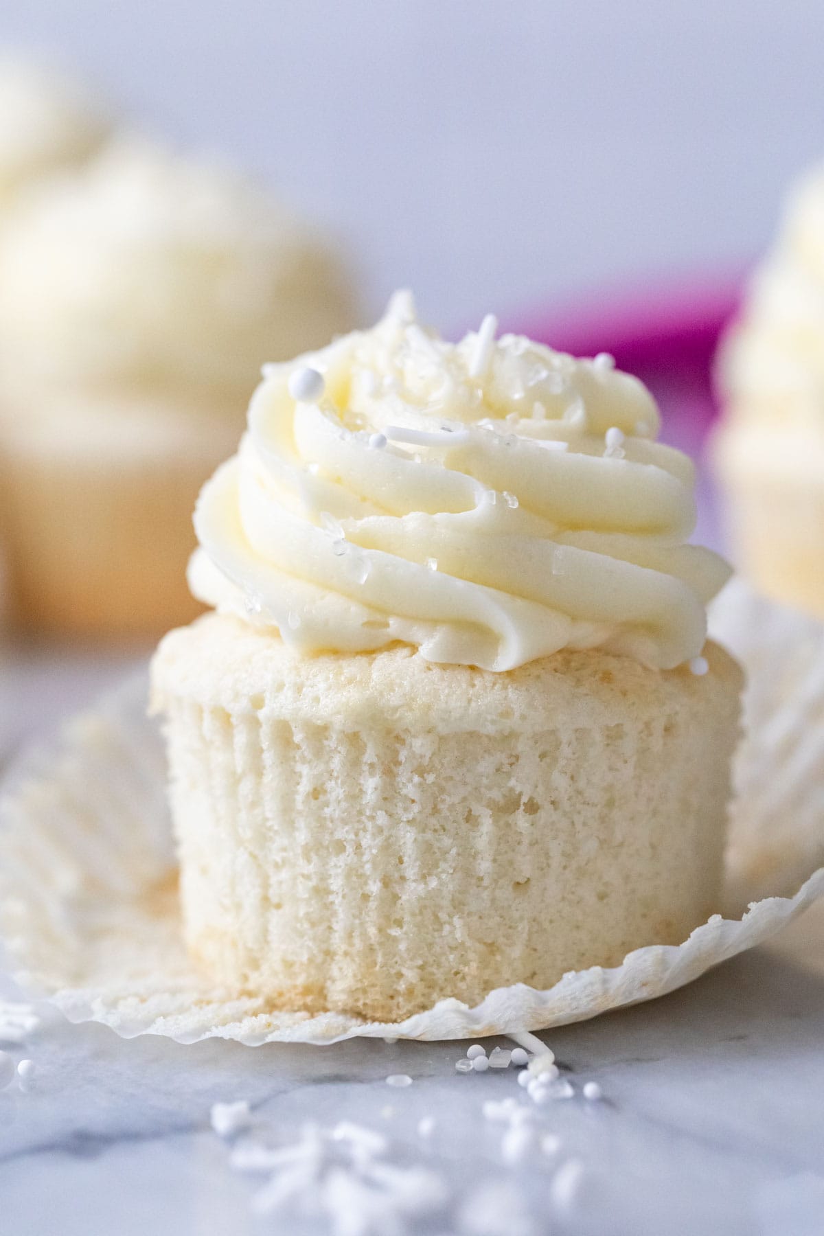White cupcake that's been unwrapped to show a snow white crumb.