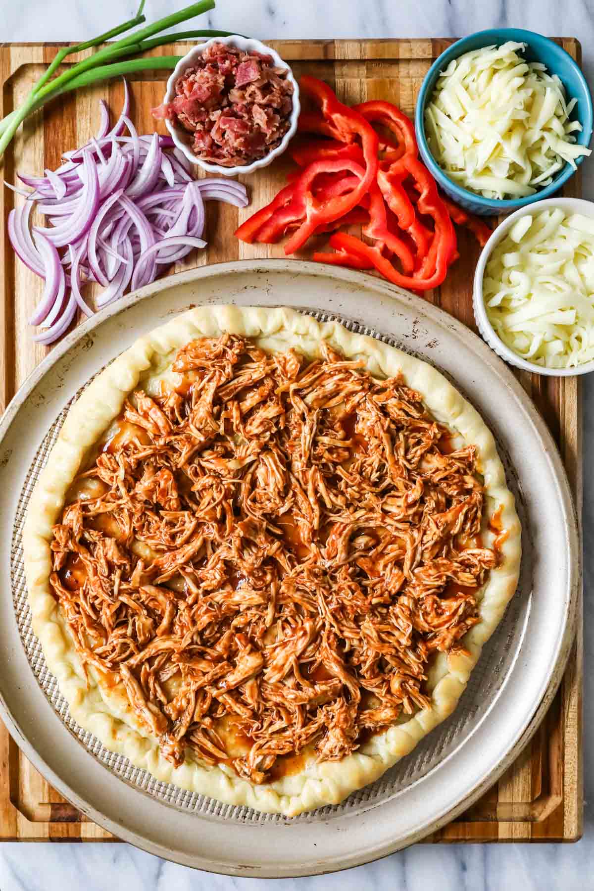 Overhead view of a pizza crust topped with BBQ chicken.