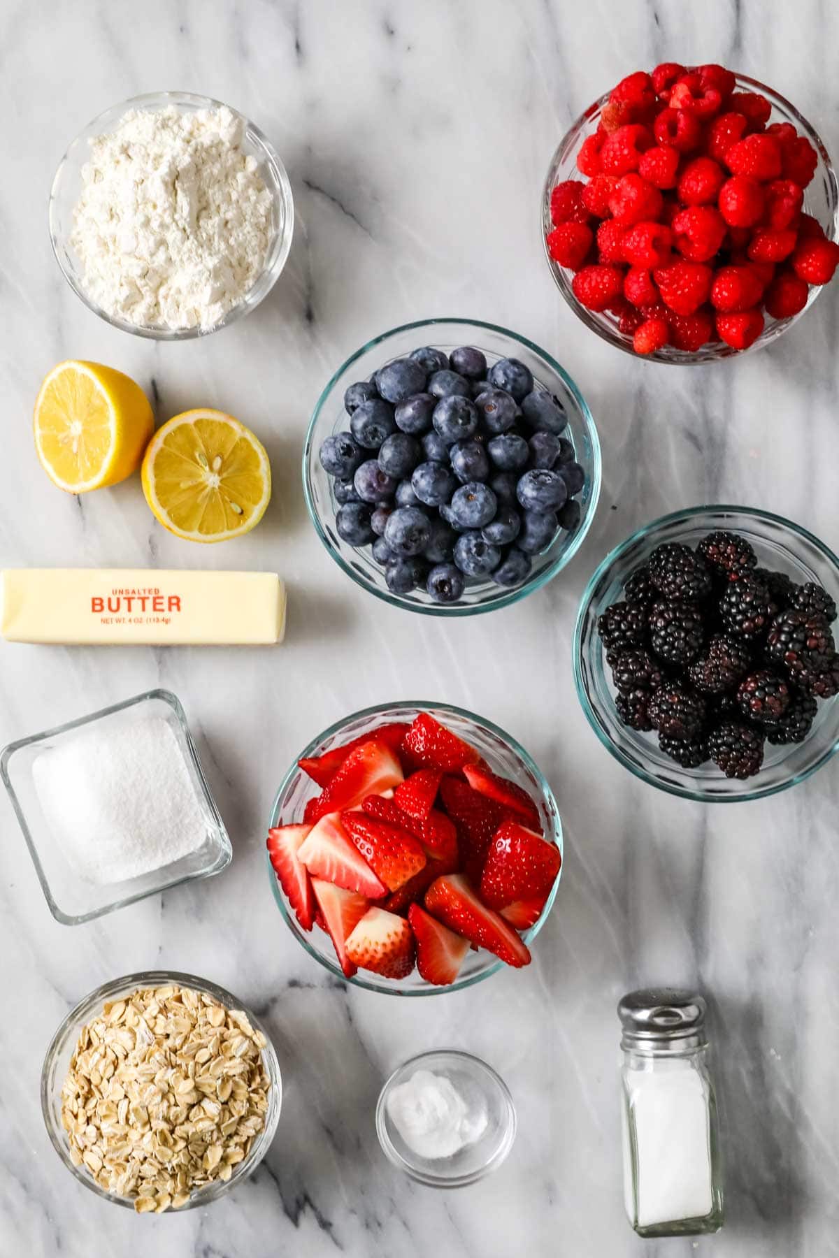 Overhead view of ingredients including berries, lemon, flour, oats, and more.