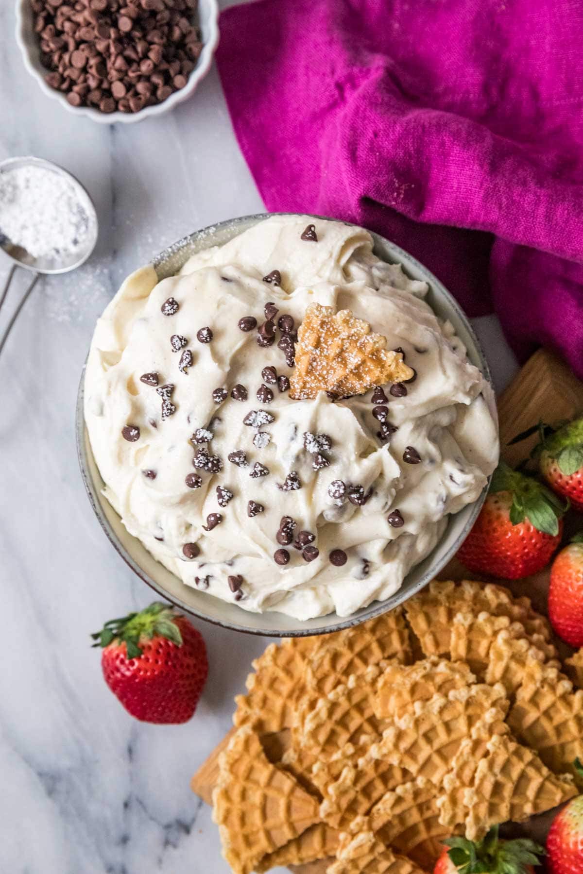 Overhead view of a bowl of dip topped with mini chocolate chips and a pizzelle cookie.