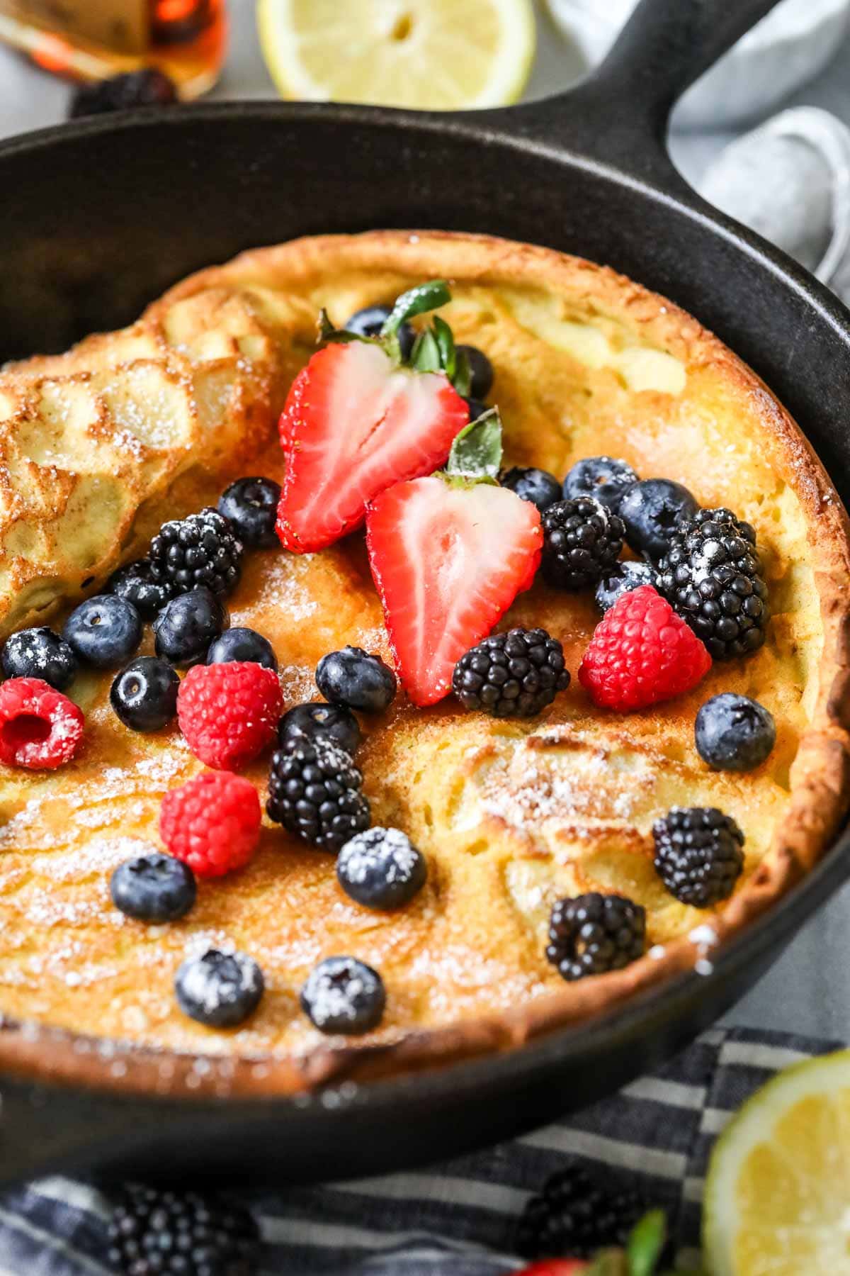 German pancake topped with berries in a cast iron pan.