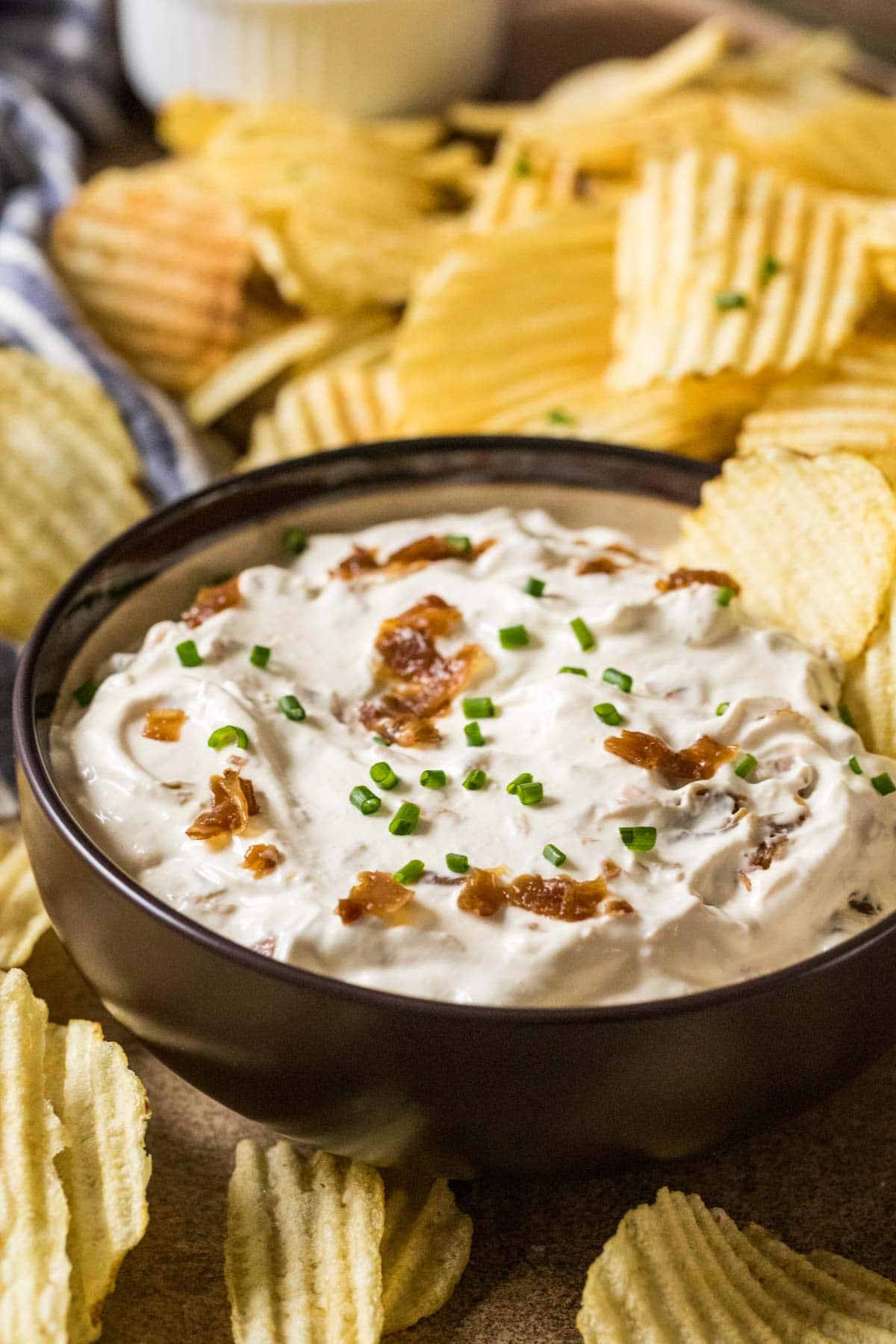 Bowl of homemade french onion dip surrounded by ripple chips.