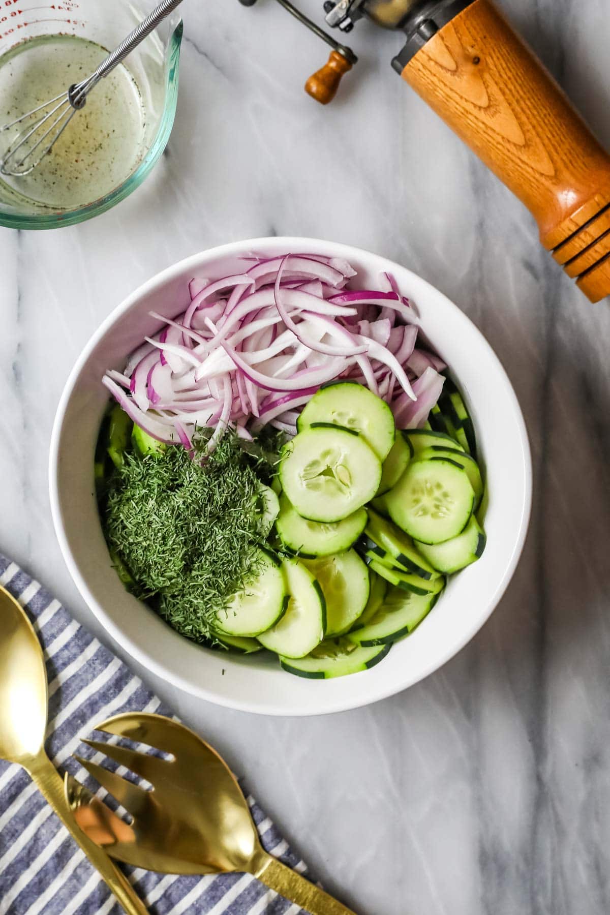 Overhead view of cucumber salad ingredients in a bowl before adding dressing.