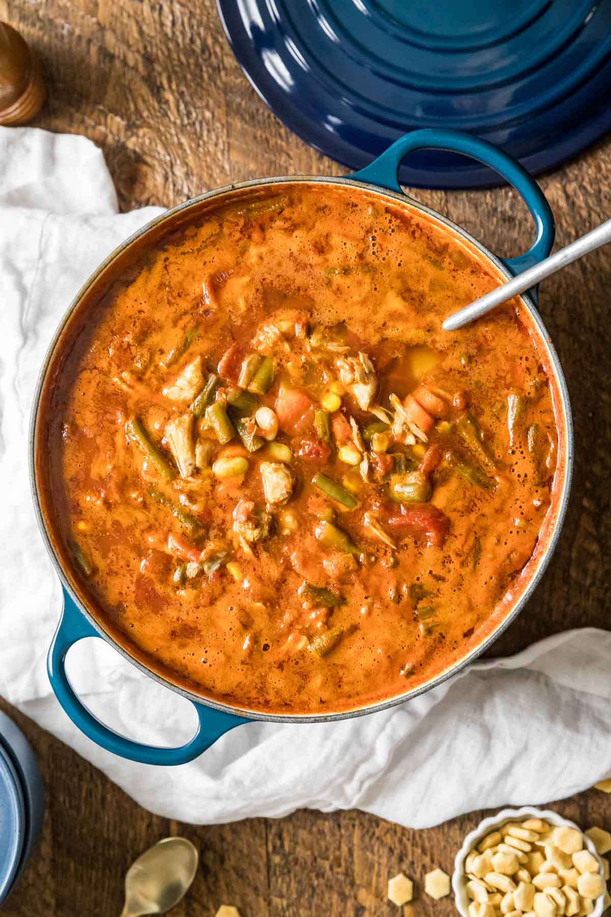Overhead view of a tomato based crab and vegetable soup in a dutch oven.