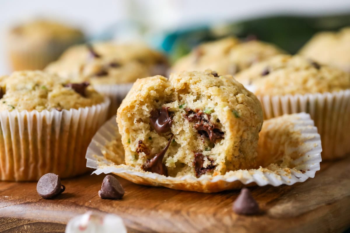Zucchini and chocolate chip muffin that's been unwrapped with one bite missing.