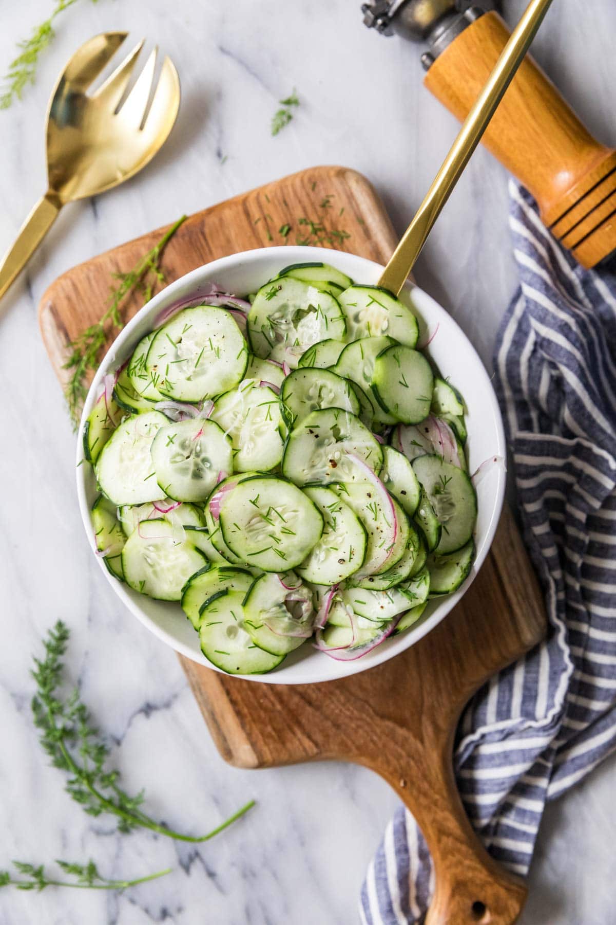 Overhead view of a serving bowl of cucumber salad made with dill and red onion.