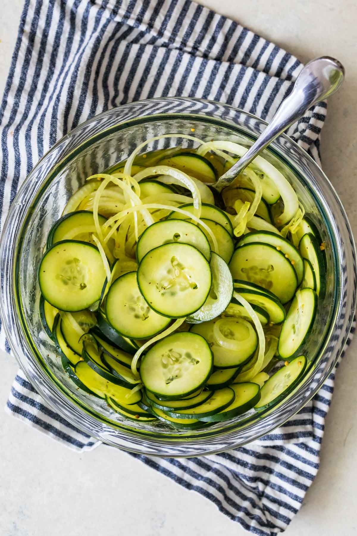 Overhead view of sliced cucumbers and onions covered in brine in a bowl.