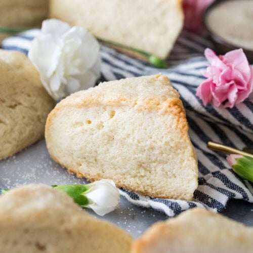 Close-up view of a tall, wedge-shaped scone surrounded by other scones on a striped towel.