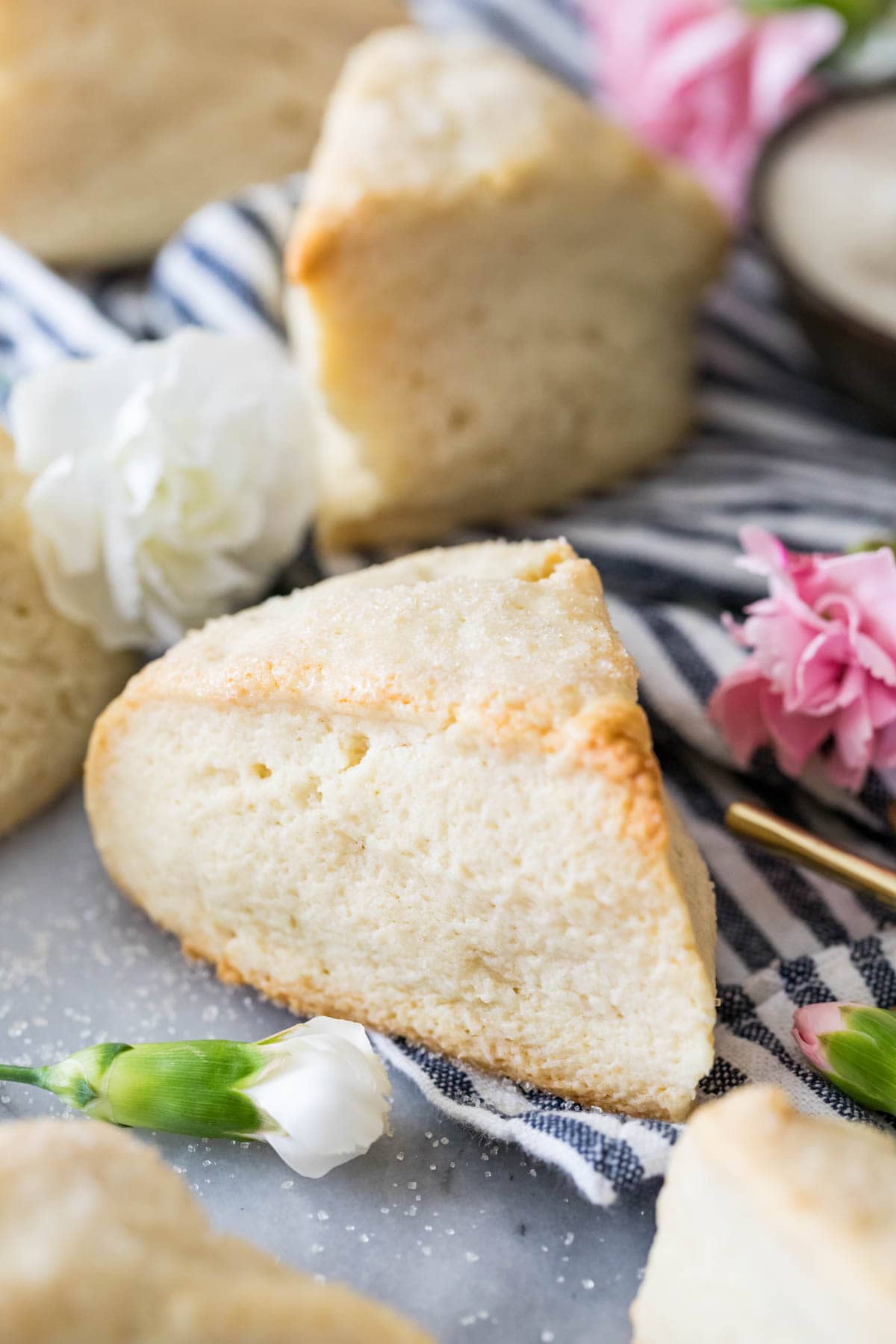 Close-up view of a tall, wedge-shaped scone surrounded by other scones on a striped towel.