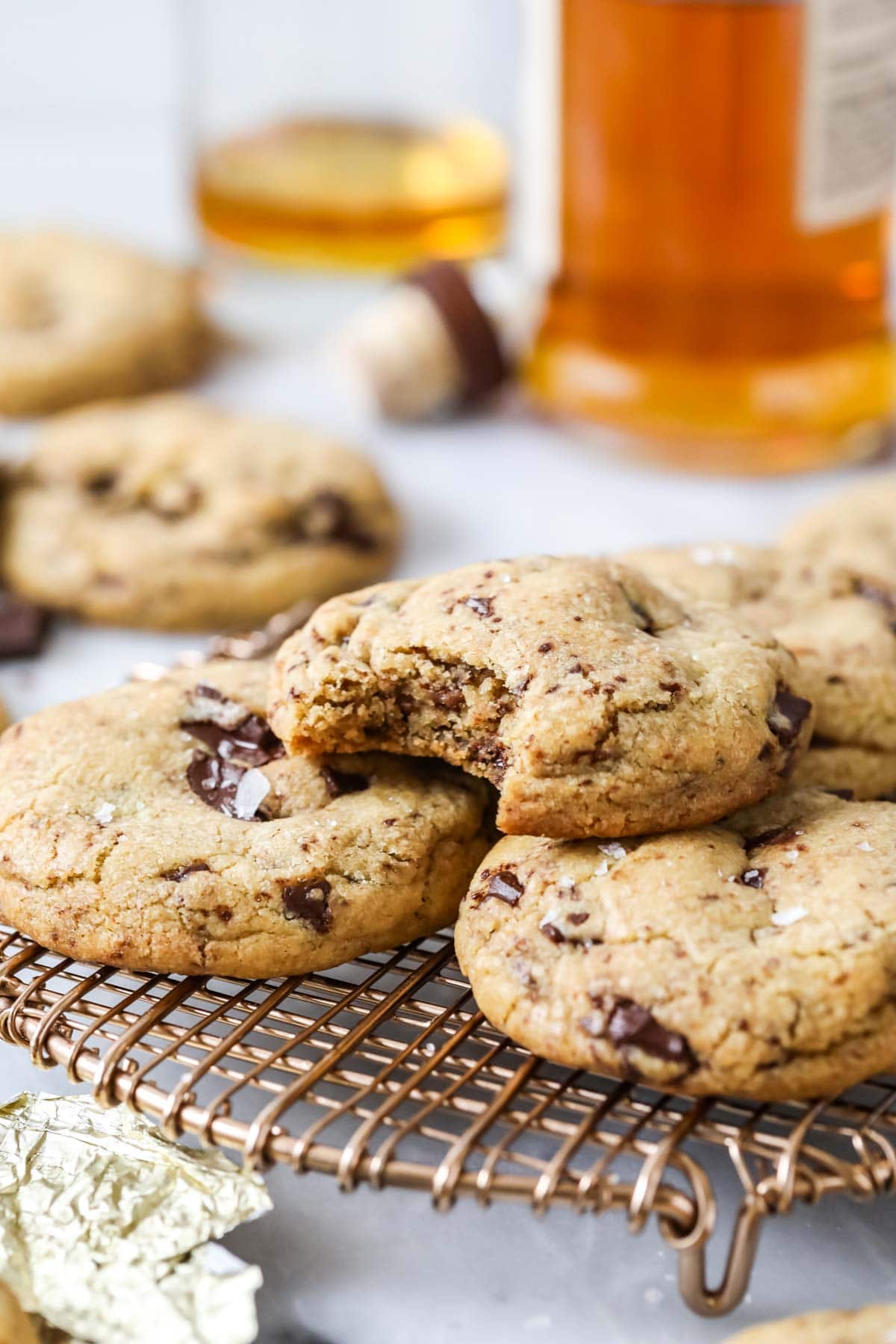 Pile of cookies made with brown butter and bourbon with the top cookie missing a bite.