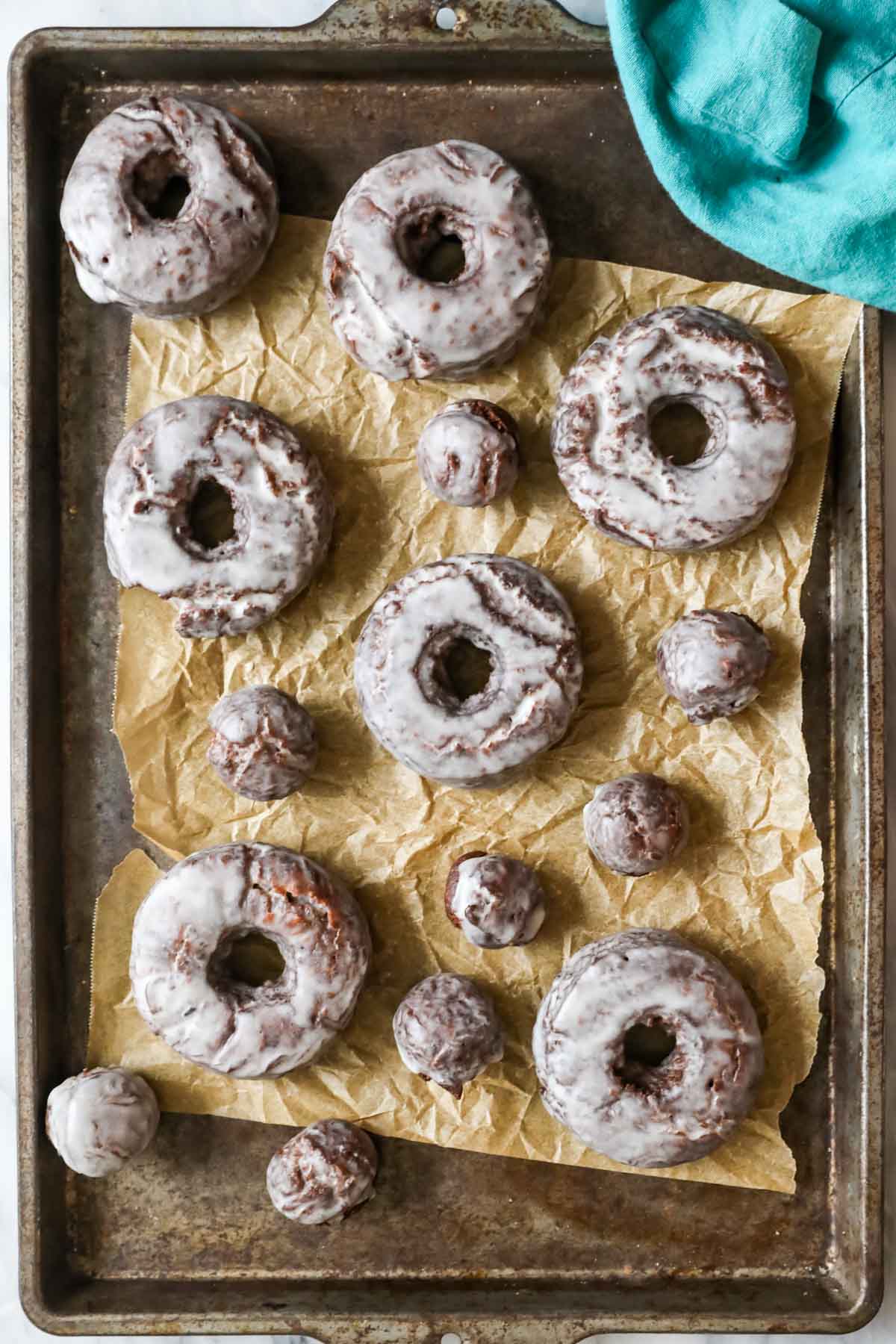 Overhead view of homemade chocolate donuts on a cookie sheet.