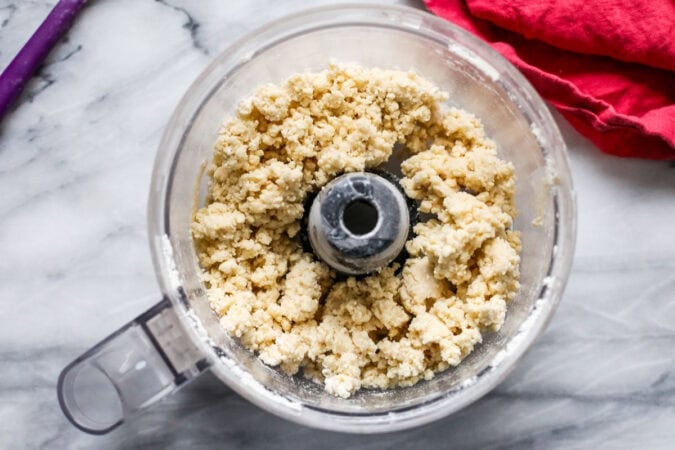 Overhead view of a shaggy sourdough pie crust in a food processor.