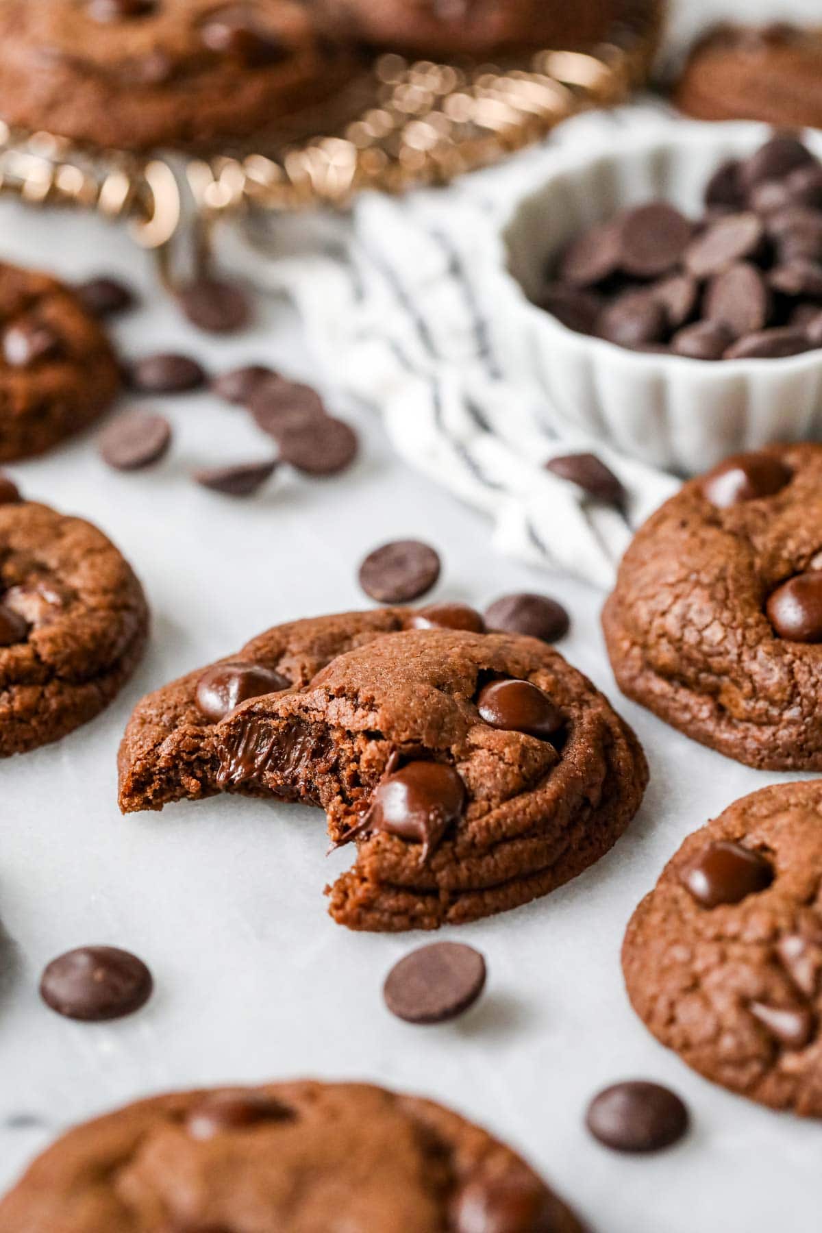 Bite missing from a chocolate cookie made with chocolate chips.