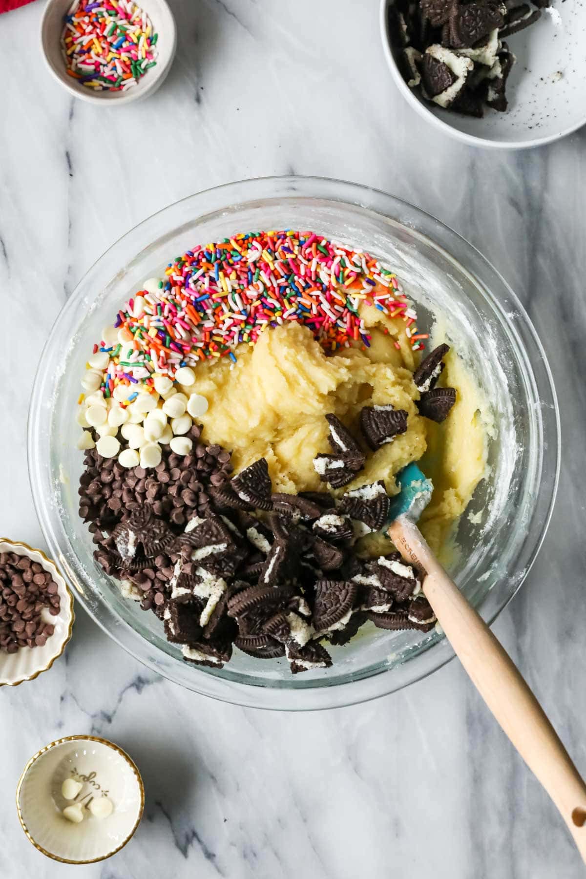 Overhead view of a bowl of dough with sprinkles and crushed Oreos added overtop.