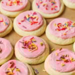 Overhead view of rows of soft frosted sugar cookies topped with pink frosting and sprinkles.