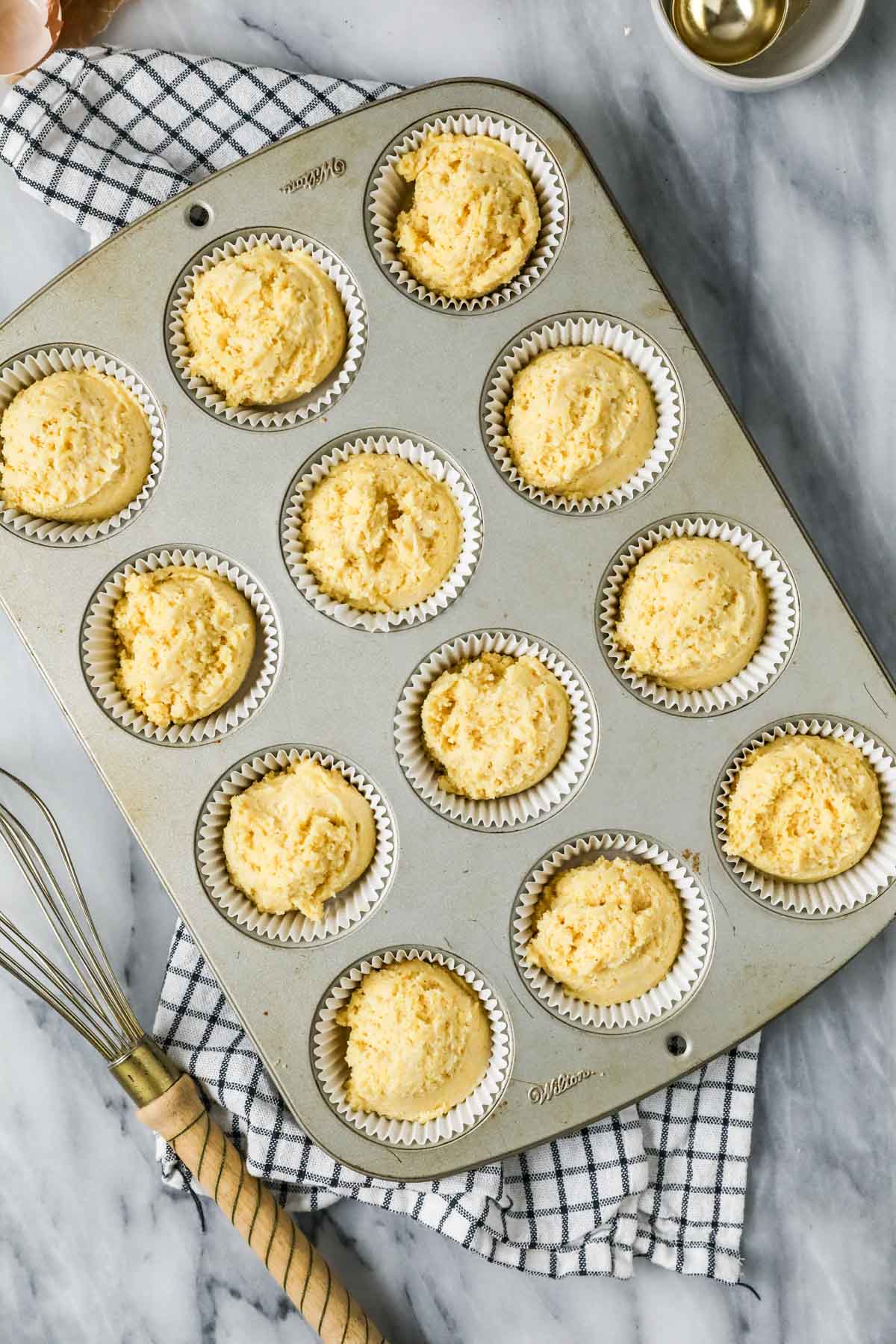 Overhead view of a muffin pan filled with batter made with cornmeal, sour cream, and more.