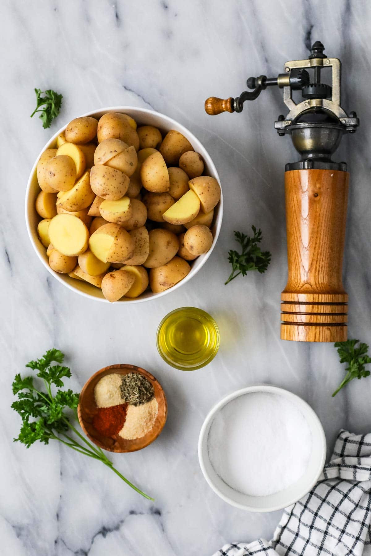 Overhead view of ingredients including potatoes, olive oil, spices, and fresh parsley.