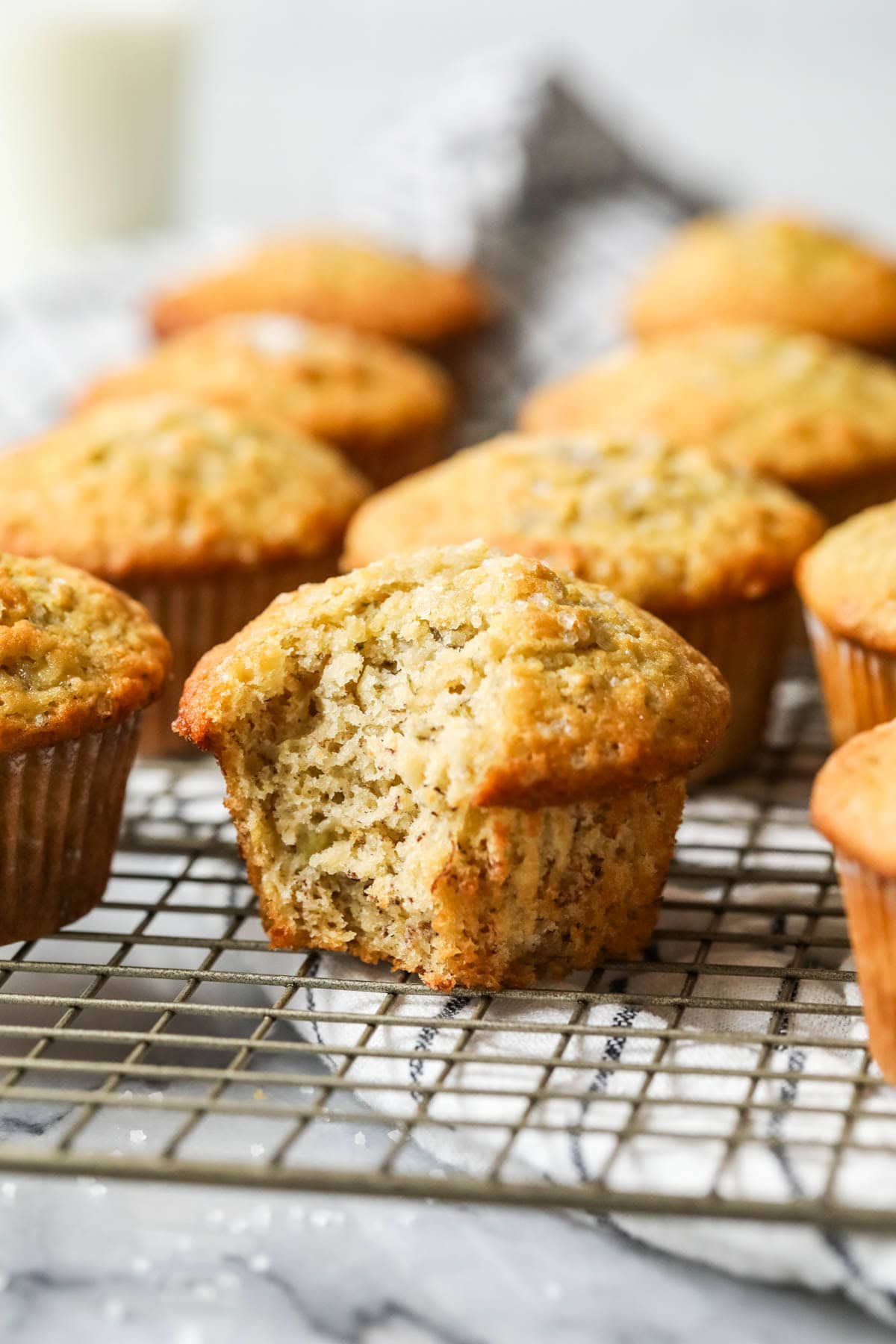 Bite missing from a sourdough banana muffin on a cooling rack.