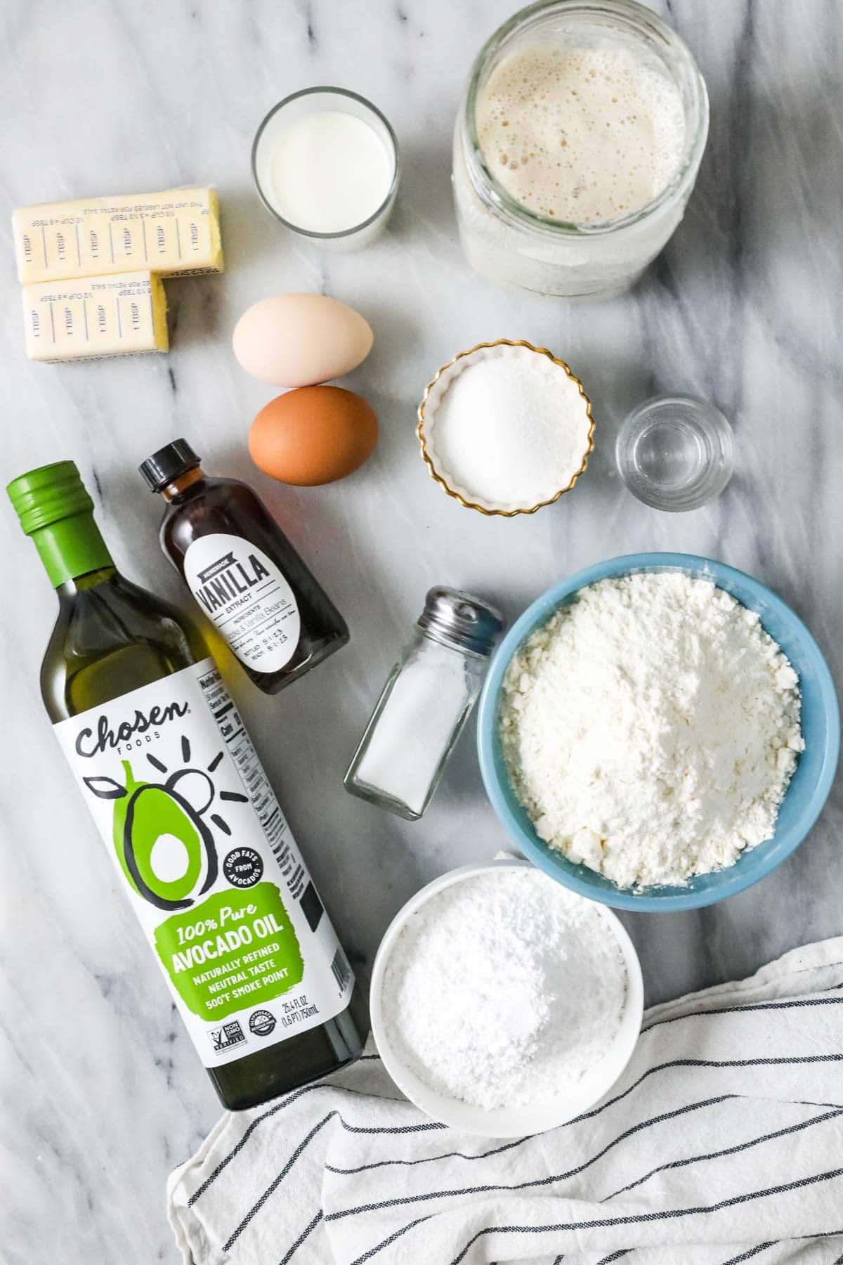 Overhead view of ingredients including sourdough starter, avocado oil, powdered sugar, and more.