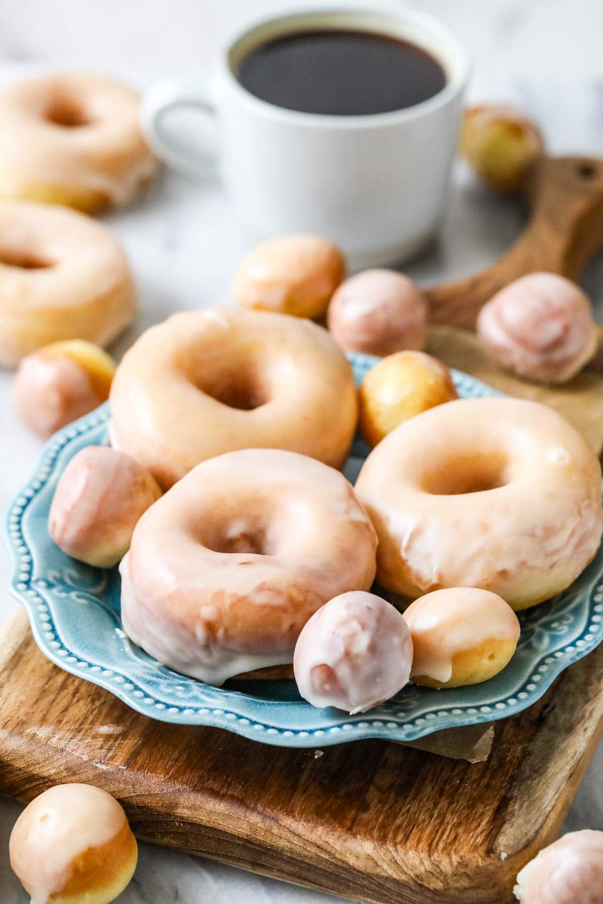 Plate of sourdough donuts and donut holes that have been dipped in a vanilla glaze.