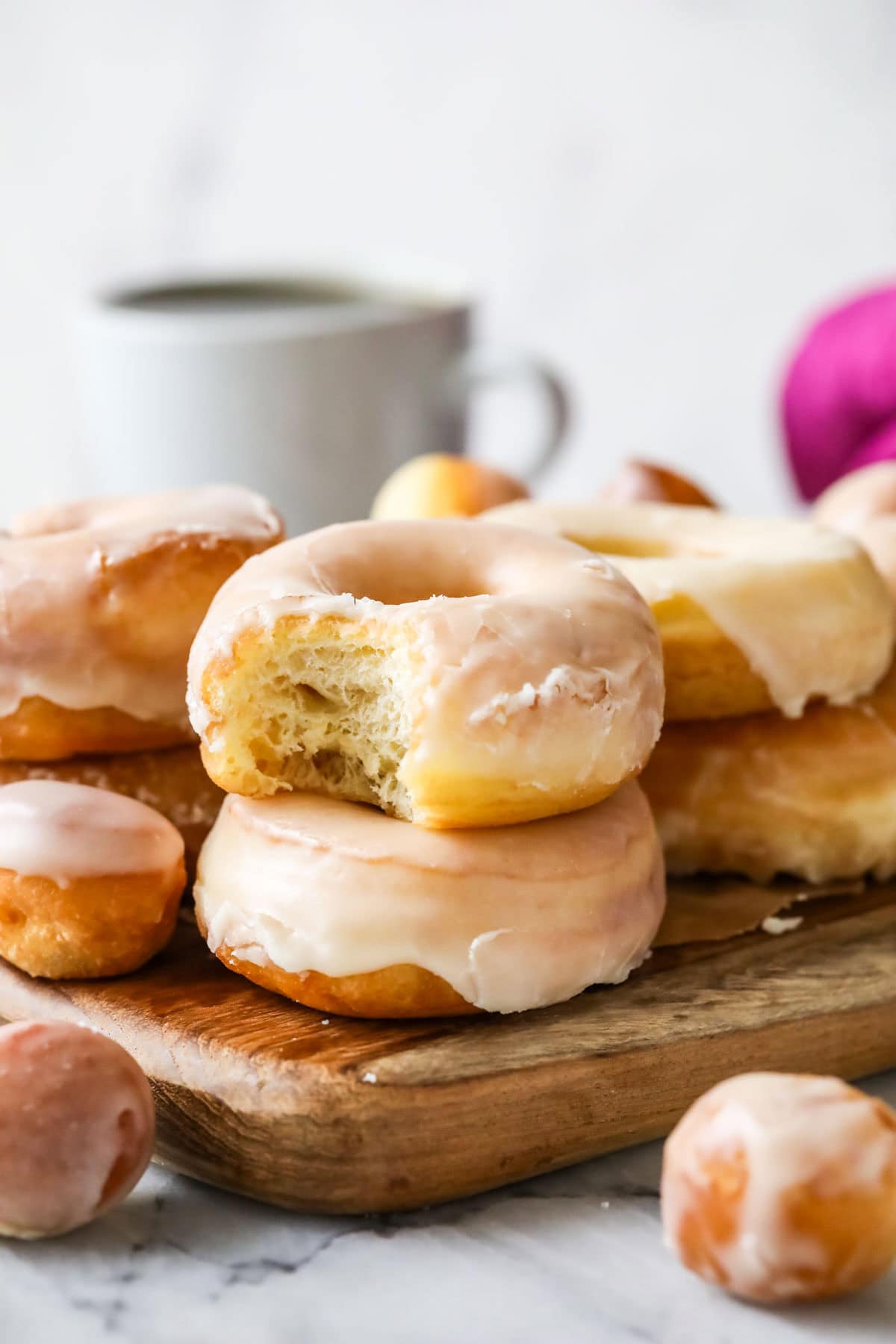 Two sourdough donuts stacked on top of each other with the top donut missing a bite.