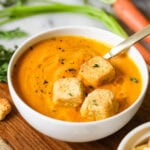 Bowl of roasted carrot soup topped with croutons.
