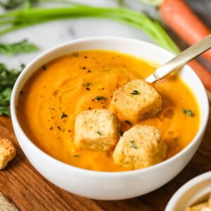 Bowl of roasted carrot soup topped with croutons.