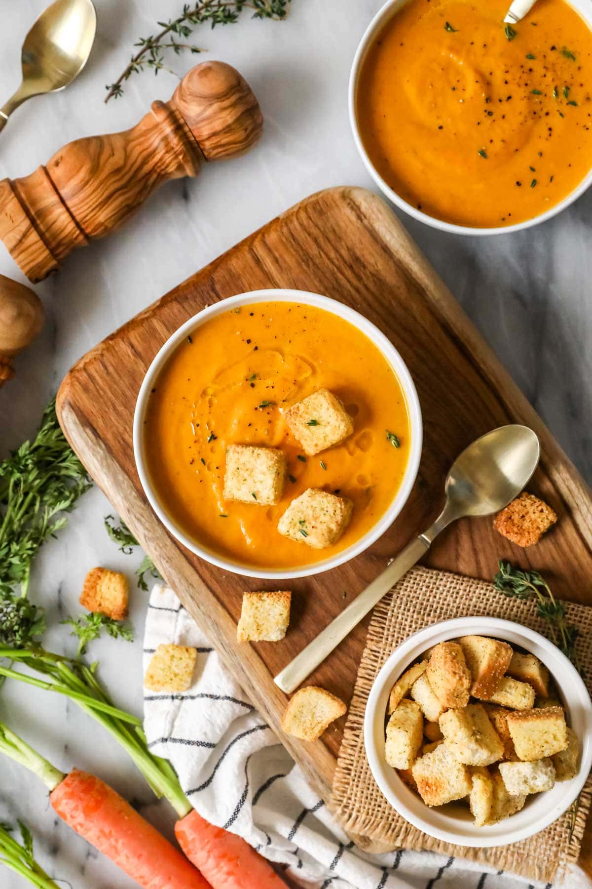 Overhead view of a bowl of carrot soup topped with croutons.