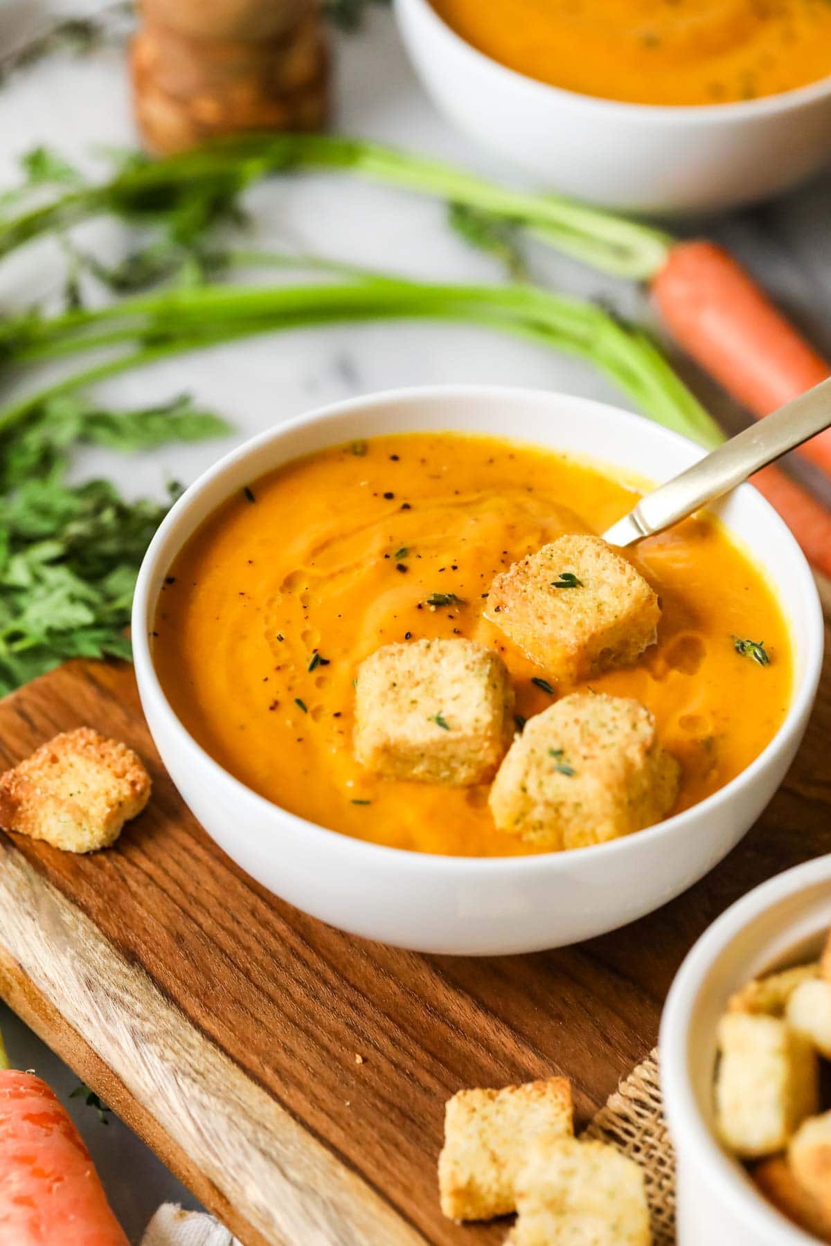 Bowl of roasted carrot soup topped with croutons.