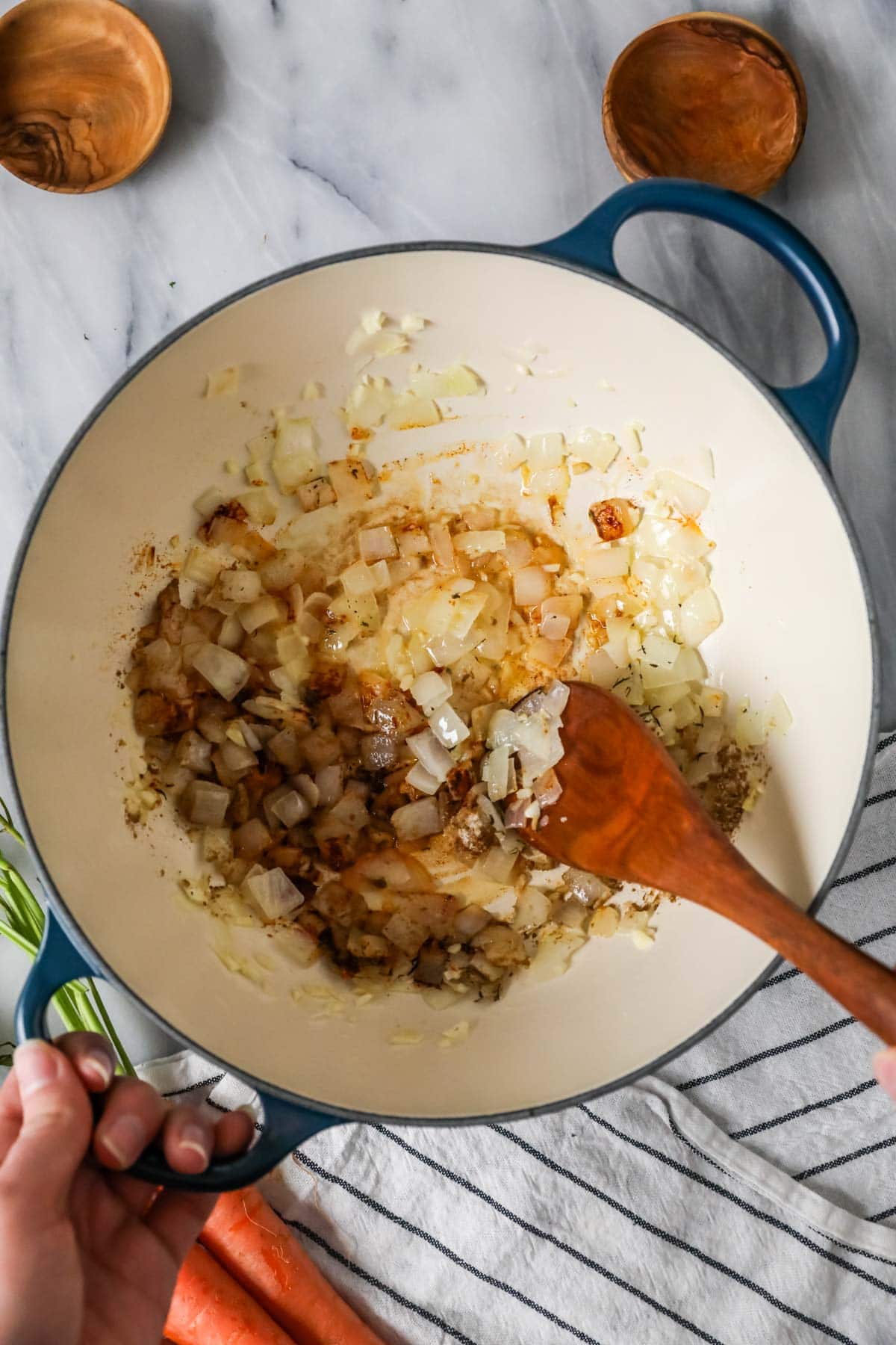 Overhead view of a dutch oven with onions and spices sauteing inside.