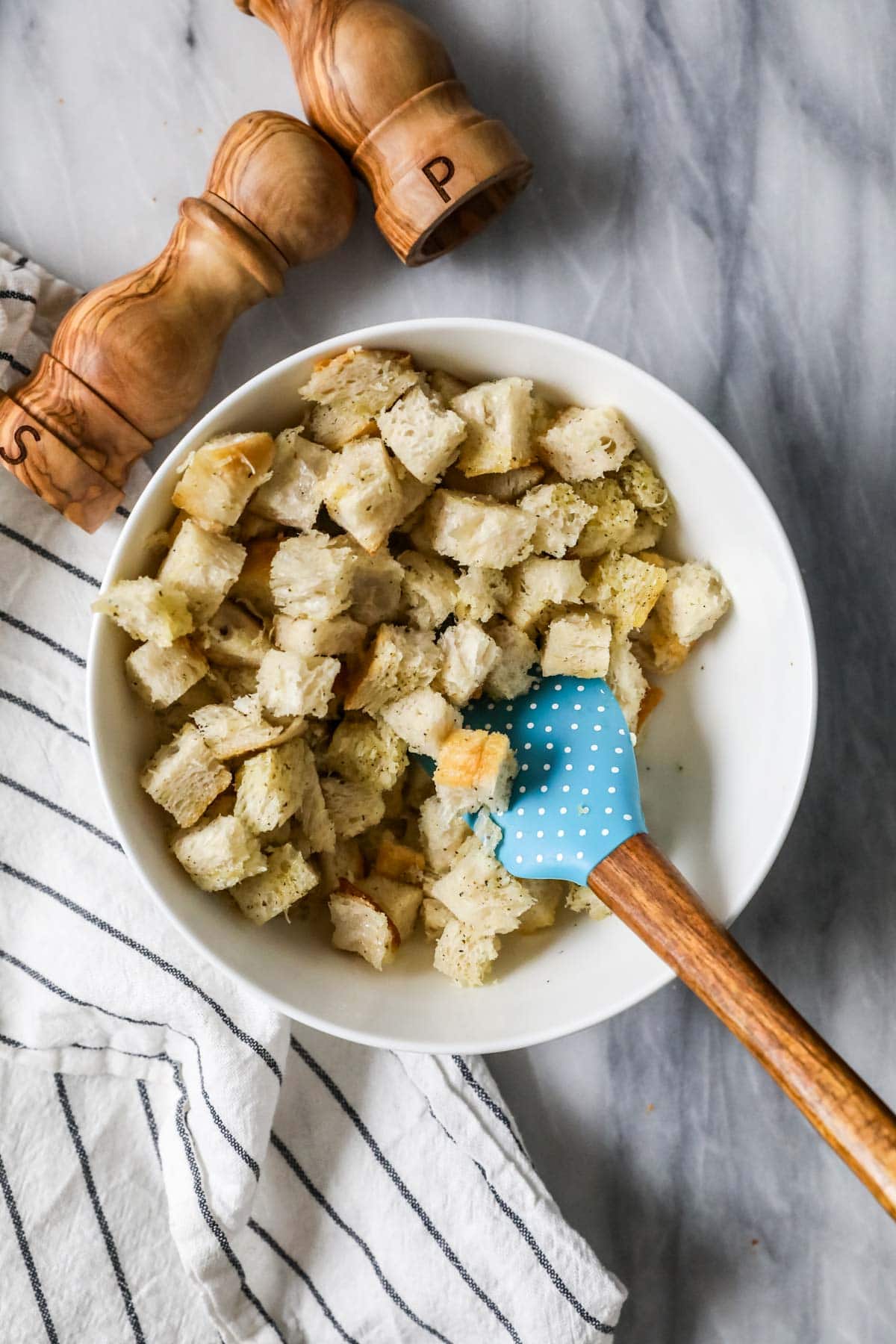 Overhead view of a bowl of bread cubes that have been tossed in olive oil.