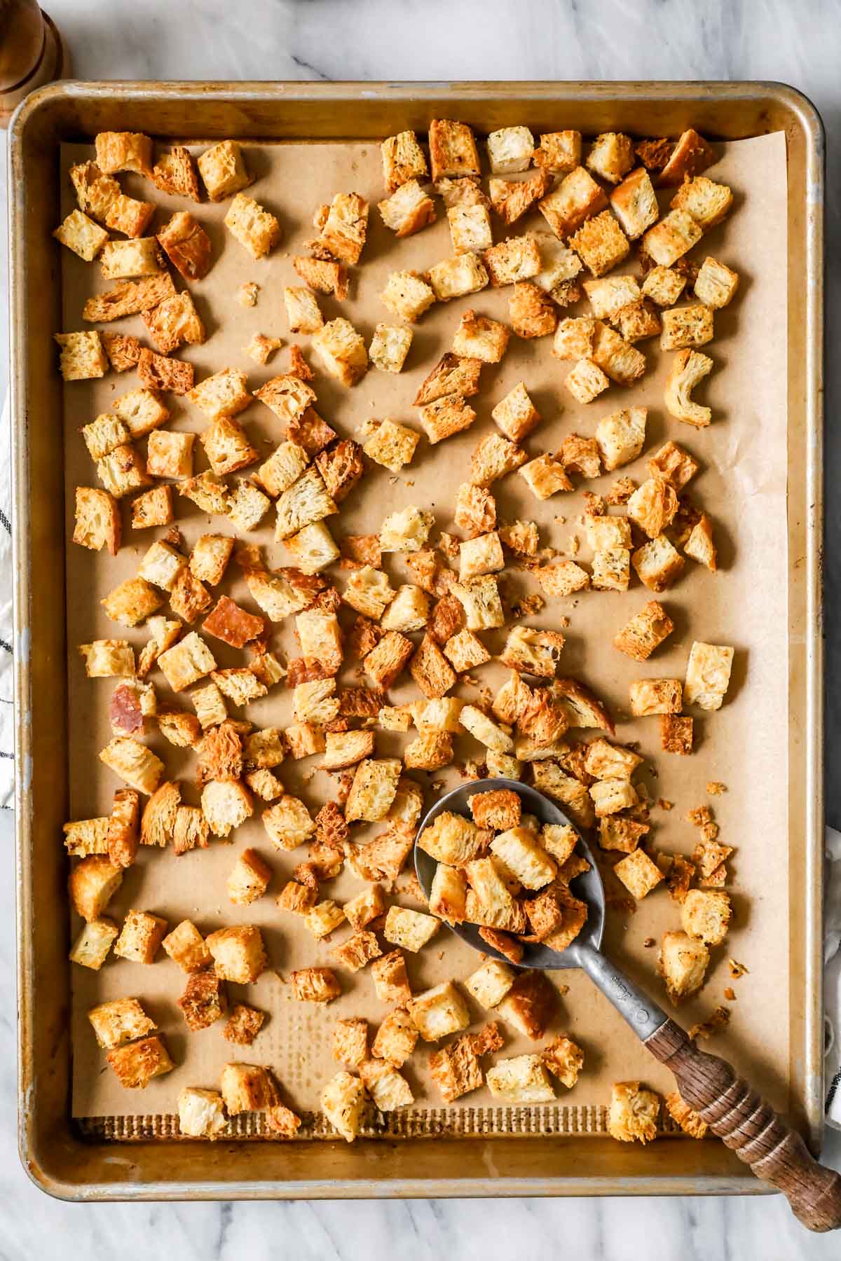 Overhead view of a baking sheet of homemade croutons after baking.
