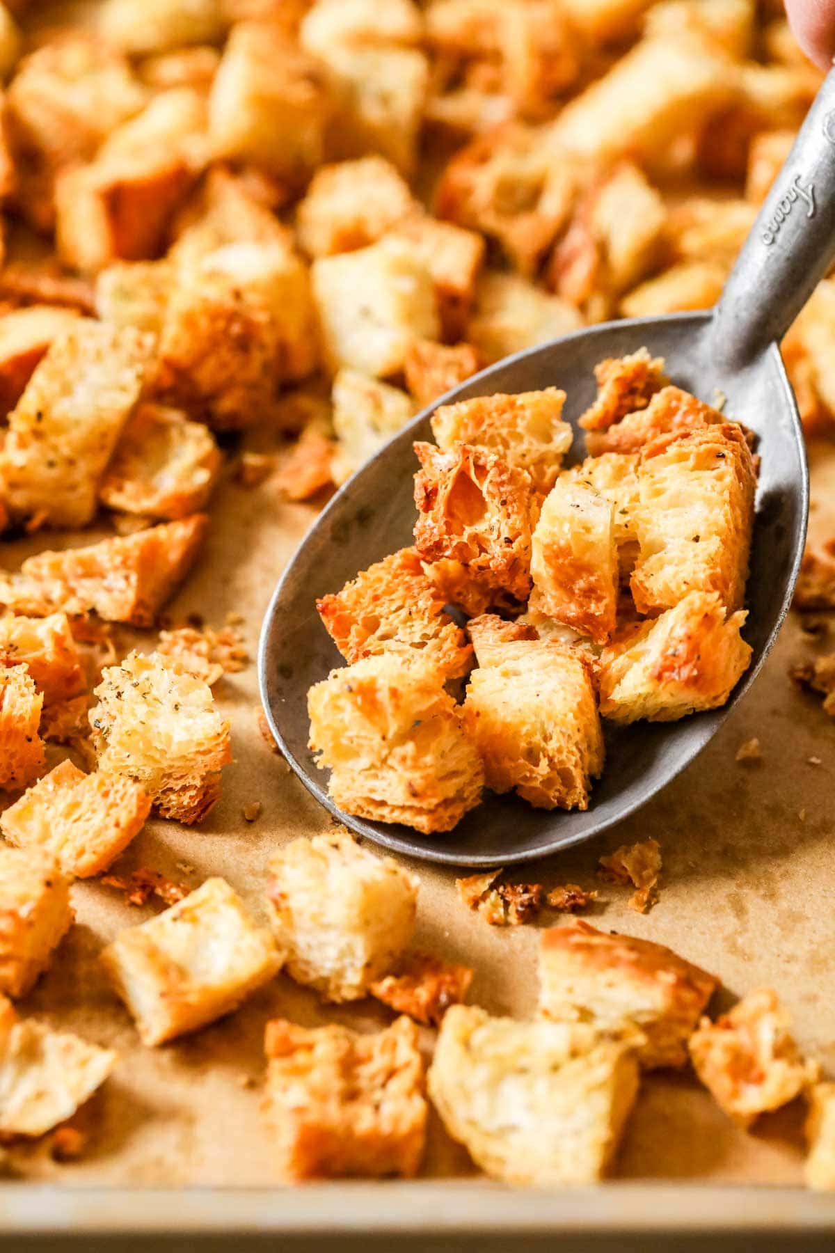 Homemade croutons being scooped off a a baking sheet.