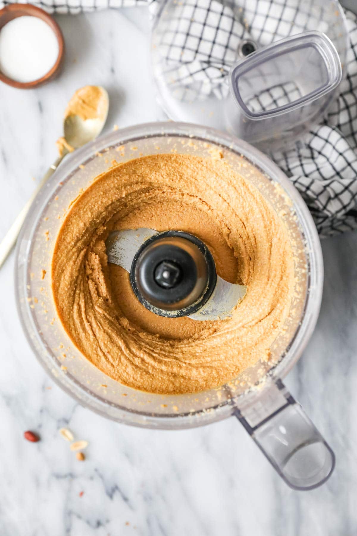Overhead view of a food processor with homemade peanut butter inside.